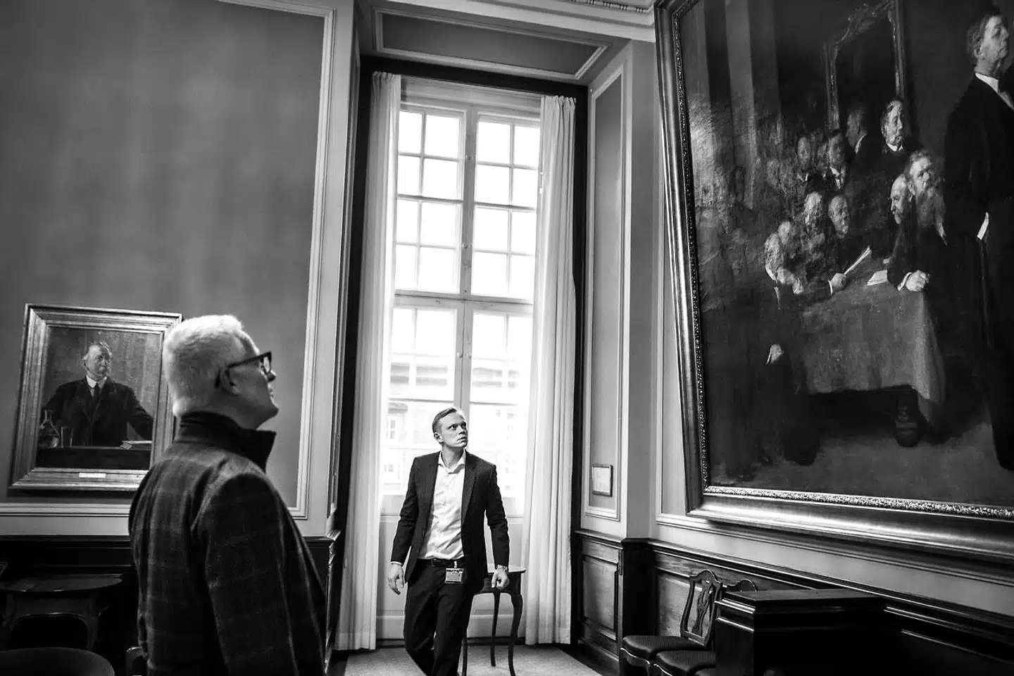 Herman Vedels maleri fra 1917 »Fra forhandlingerne om Grundloven 5. juni 1915« fylder hele den ene endevæg i Samtaleværelset på Christiansborg og er blevet et symbol på den vigtigste hjørnesten i demokratiet. Nu vil Grundfos' topchef Mads Nipper (tv.) og Anders Fæste,  dansk landechef for Boston Consulting Group, have den ændret.