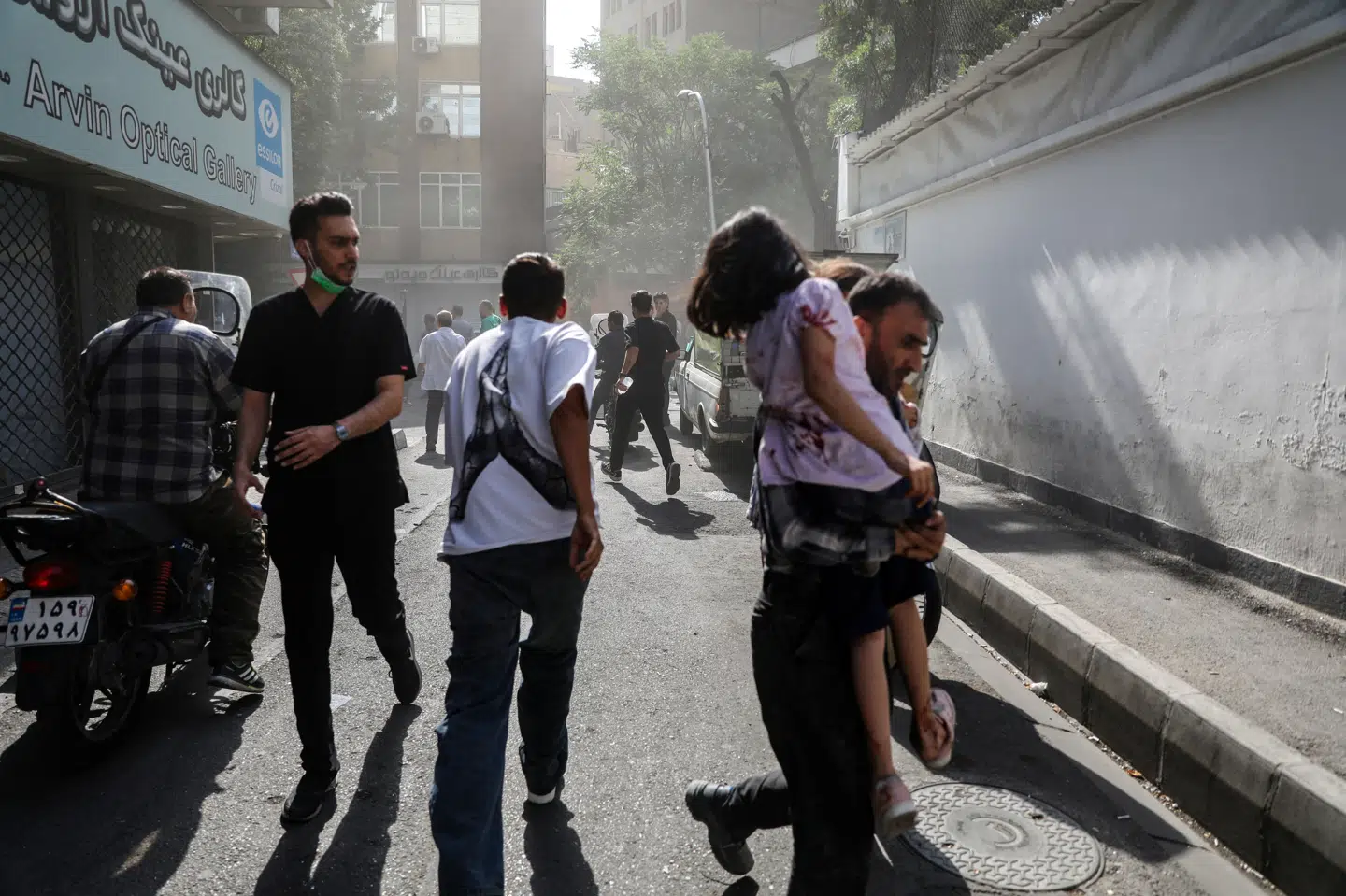 Folk løber gennem en gade i Irans hovedstad, Teheran, efter et israelsk angreb søndag. Ifølge en talsmand for landets sundhedsministerium har 224 mistet livet, langt størstedelen civile.