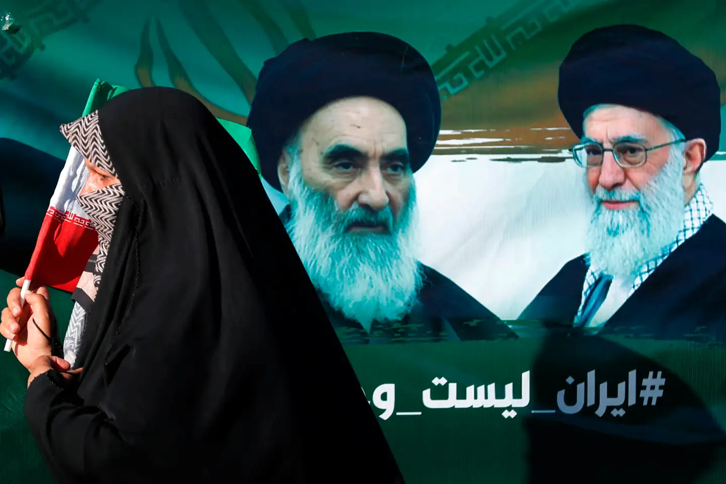 En iransk kvinde går forbi et portræt af Irans øverste shiamuslimske leder, storayatollah Ali al-Sistani, og Irans øverste åndelige leder, ayatollah Ali Khamenei.