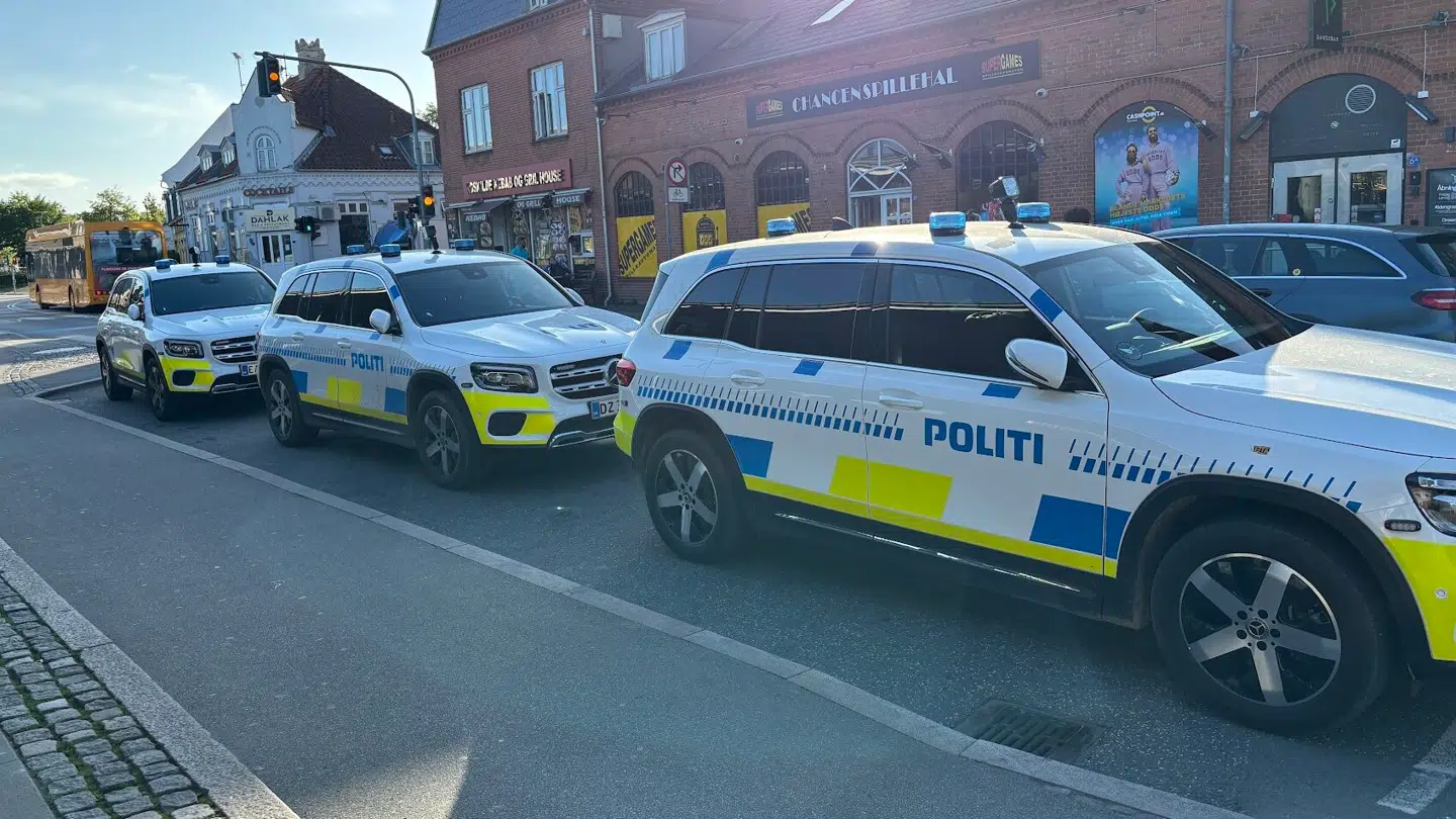 Flere politibiler er parkeret foran indgangen til stationen.