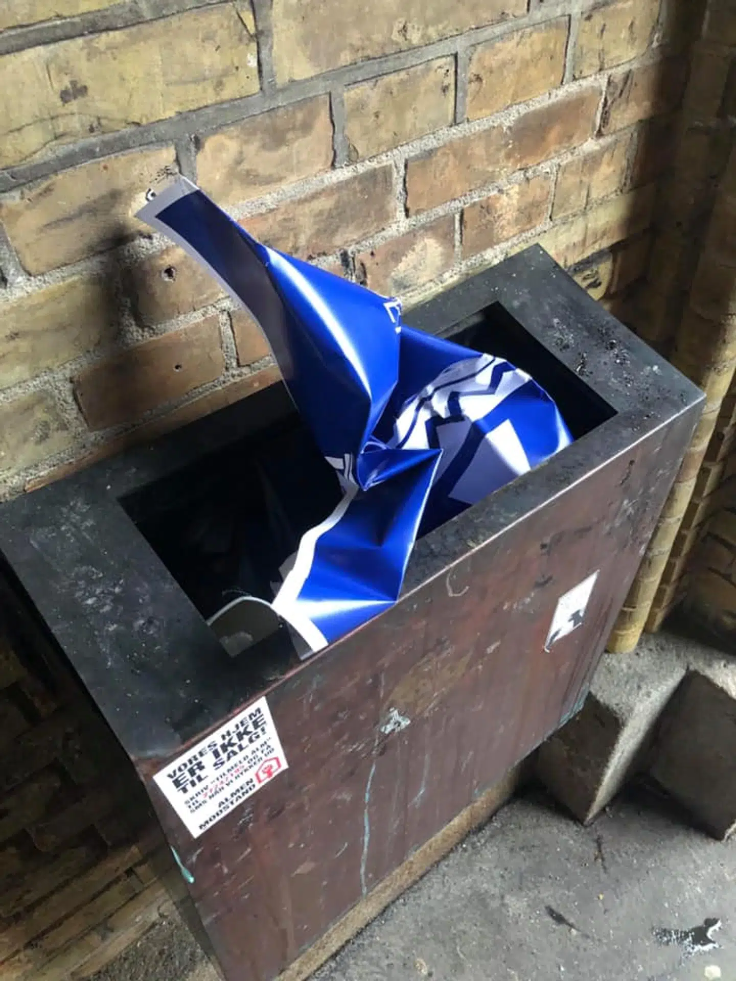 En plakat er smidt i skraldespanden.