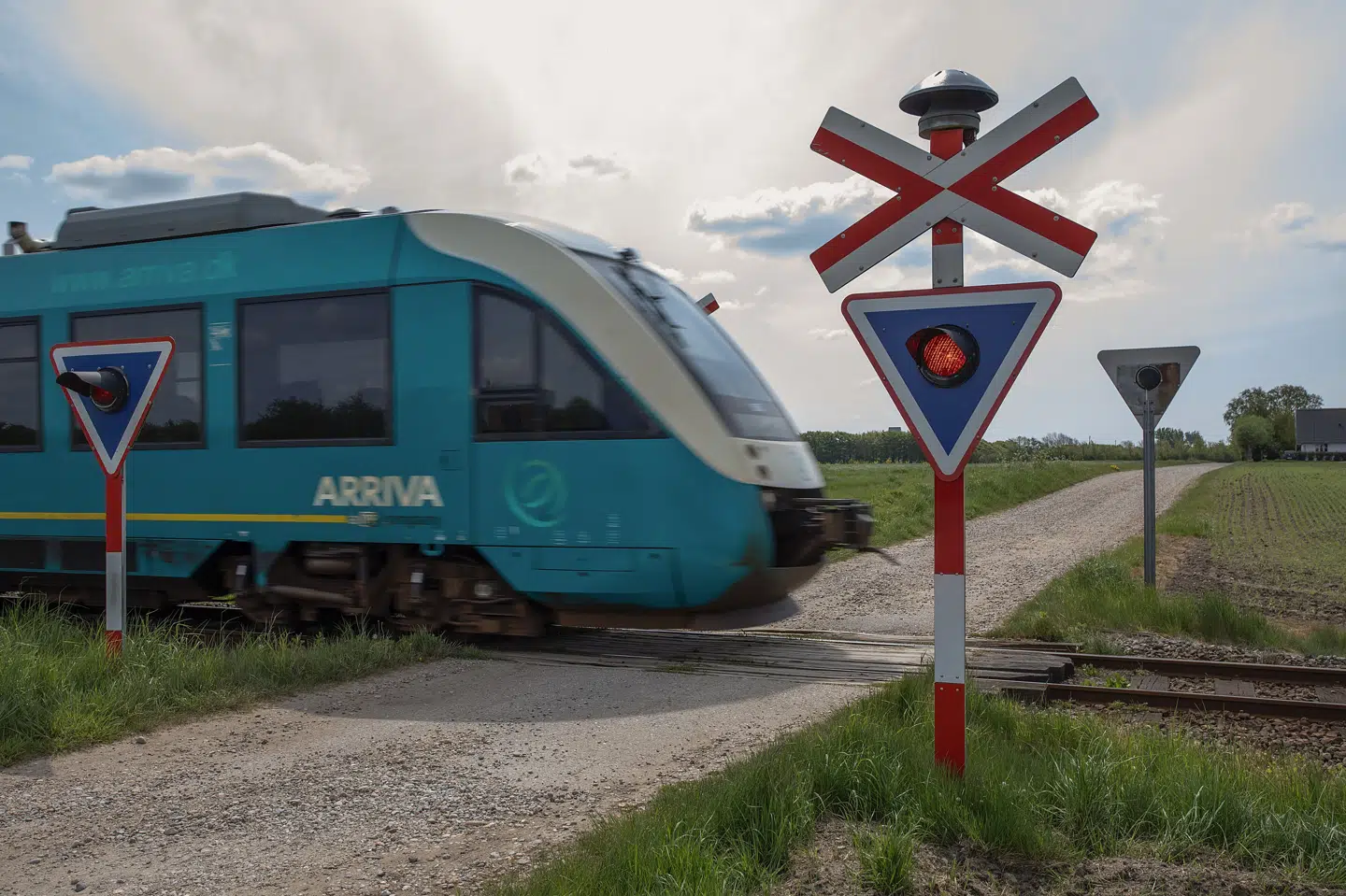 Et Arriva-tog passerer en ubevogtet jernbaneoverskæring på Tørvevej ved Billum i Varde Kommune. Da en 24-årig mand mistede livet ved Kliplev lørdag, manglede en klokke ved den pågældende jernbaneoverkørsel. Tirsdag er en 50-årig mand sigtet for at have stjålet klokker i Sønderjylland, og det skal efterforskes, om der er forbindelse til dødsulykken, oplyser politiet. (Arkivfoto).