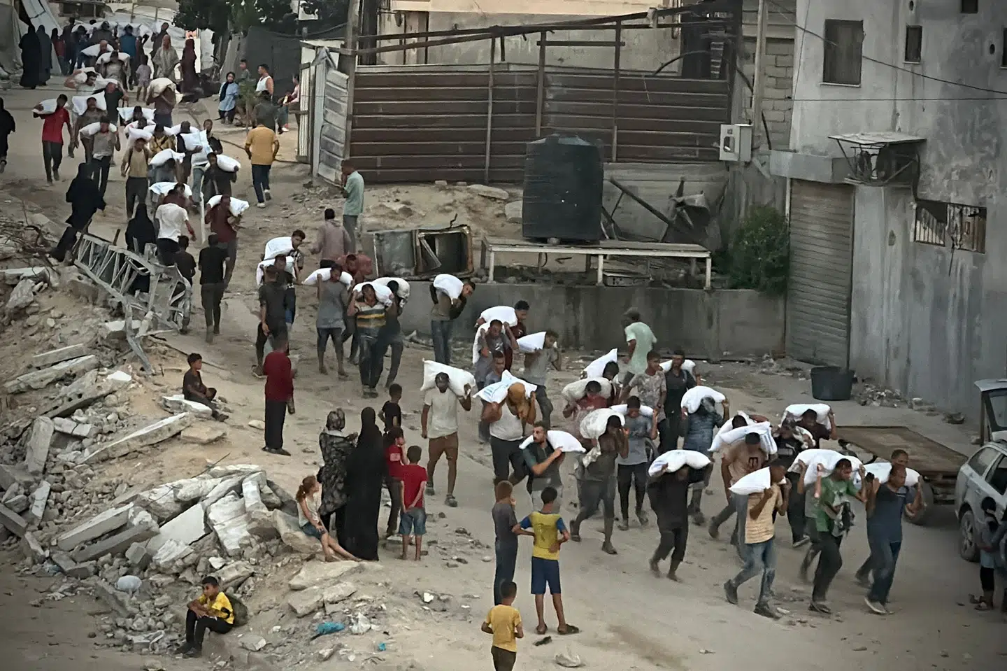 Mænd bærer på sække med mel, som de har plyndret fra en lastbil med nødhjælp tirsdag i Khan Yunis i den sydlige del af Gazastriben.