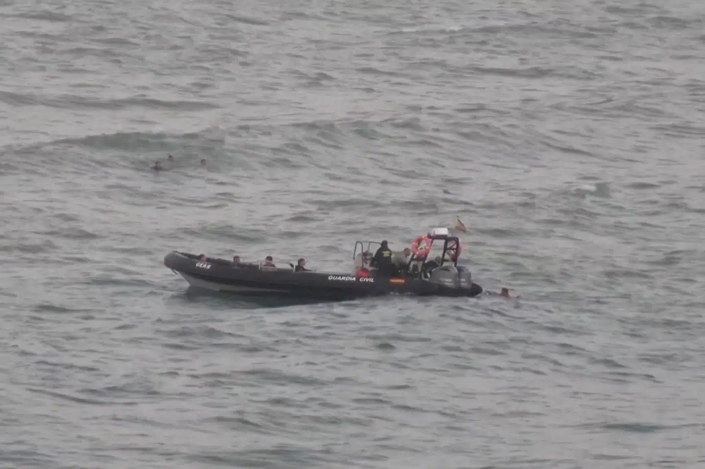 En migrant ligger i vandet ved siden af en af det spanske civilberedskabs både, mens andre migranter svømmer i baggrunden. Det lykkedes mindst 54 børn og omkring 30 voksne at svømme fra Marokko til den spanske eksklave Ceuta.