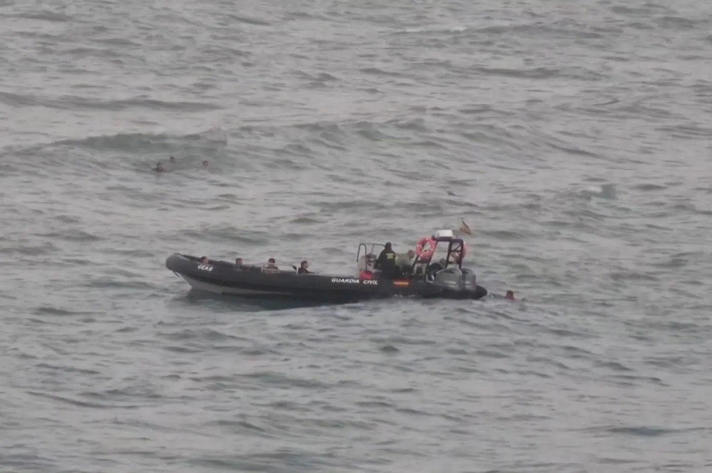En migrant ligger i vandet ved siden af en af det spanske civilberedskabs både, mens andre migranter svømmer i baggrunden. Det lykkedes mindst 54 børn og omkring 30 voksne at svømme fra Marokko til den spanske eksklave Ceuta.