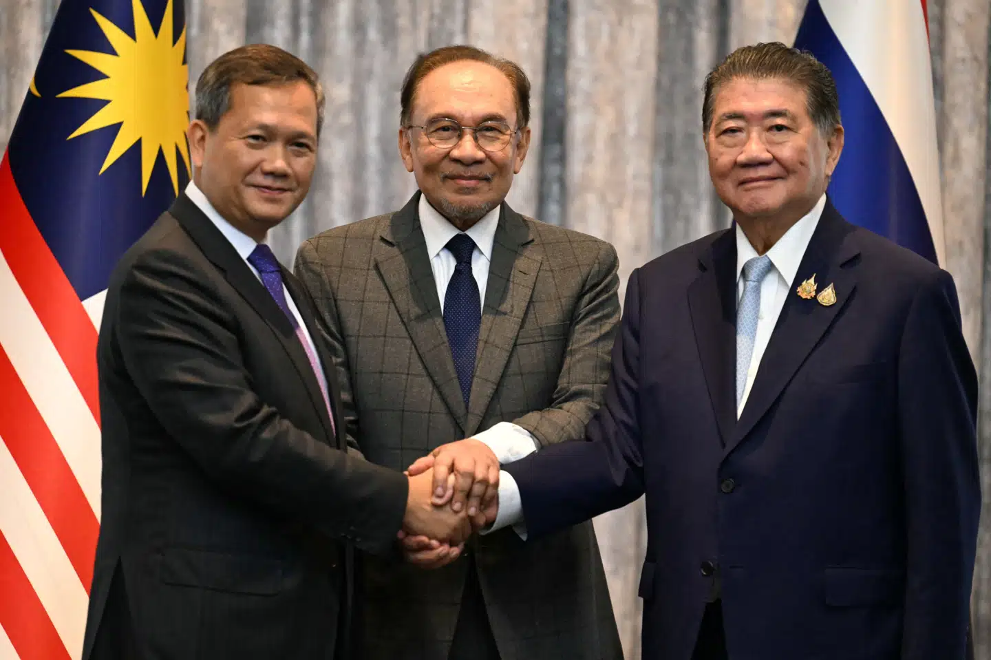 Cambodjas premierminister, Hun Manet (til venstre), Malaysias premierminister, Anwar Ibrahim (i midten), og Thailands fungerende premierminister, Phumtham Wechayachai (til højre), giver hånd under indgåelse af en våbenhvileaftale mandag. (Akrivfoto).