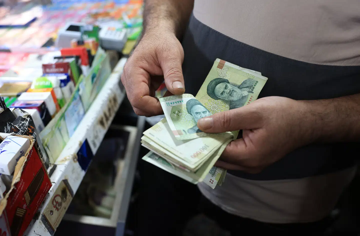 En butiksejer i Irans hovedstad, Teheran, tæller pengesedler på 100.000 rial. Nu vil Iran skære fire nuller væk og dermed gøre valutaen lettere at bruge i dagligdagen.