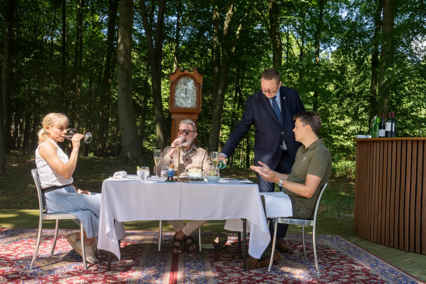 Der er dækket op i skoven på Fænø. Fra venstre Simon Skouboes kæreste, Stephanie Skov, Søren Frank og Simon Skouboe. André Larsen fra Henne Kirkeby Kro serverer. Skouboe-familien er blandt de danske velhavere, der har investeret en del af formuen i at drive fine dining-restauranter.