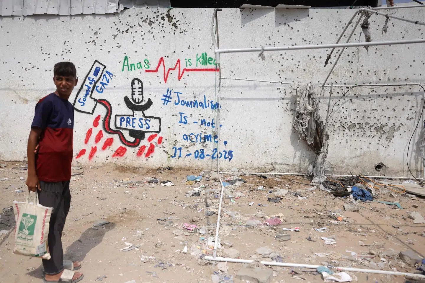 En palæstinensisk dreng står foran en væg med graffiti på stedet, hvor et dødeligt israelsk angreb ødelagde et Al Jazeera-telt og dræbte seks journalister søndag. (Arkivfoto).