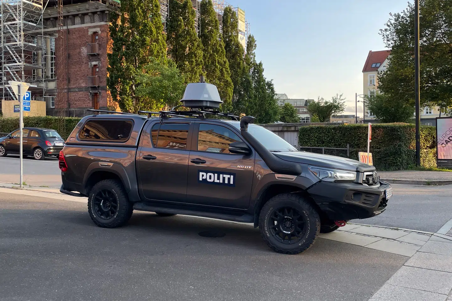 De danske myndigheder har anskaffet mindst to nye køretøjer, der har været indsat under præsident Zelenskyjs besøg i Aarhus og København. Der er tale om en Toyota Hilux med det australske DroneSentry-X Mk2-system påmonteret, der er i stand til at jamme fjendtlige droner. Anskaffelsen afspejler en voksende frygt for terrorangreb eller likvideringer med droner. Fotoet er taget i Aarhus under kortegekørsel.