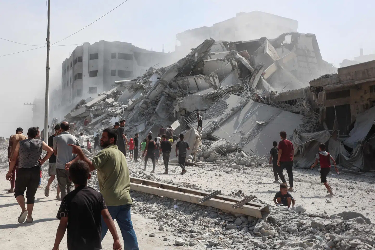 Palæstinensere samles omkring ruinerne af højhuset al-Ghafari i Gaza By. Bygningen blev ødelagt i et israelsk angreb mandag. Israels militær har varslet en fortsat offensiv i Gazastribens største by og har opfordret de hundredtusindvis af palæstinensere i byen til at forlade den.