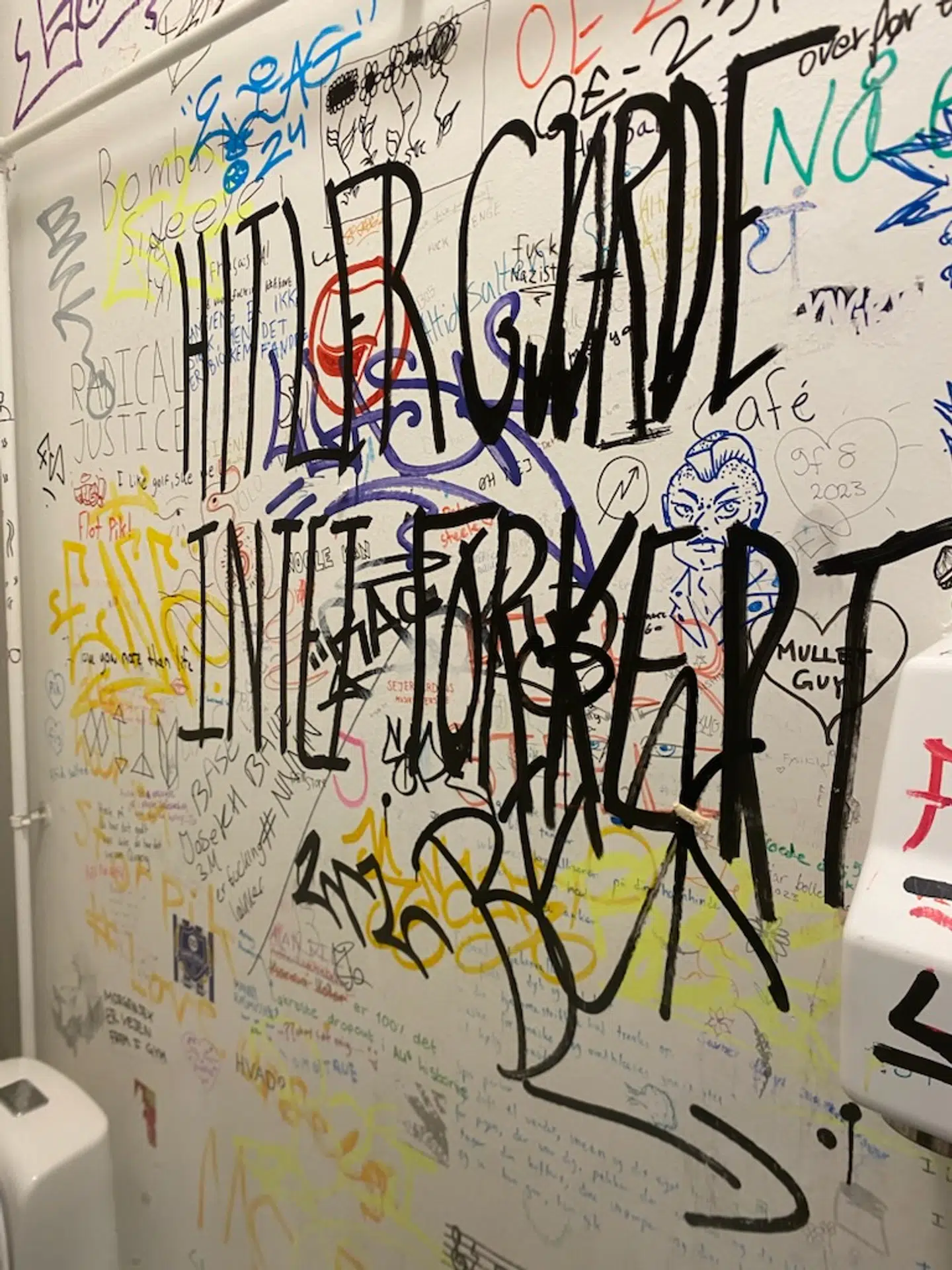 »Hitler gjorde intet forkert«, står der her. Bag det antisemitiske budskab kan desuden ses graffiti med budskabet »fuck nazister« samt et logo fra den venstreekstreme gruppering Antifascistisk Aktion.
