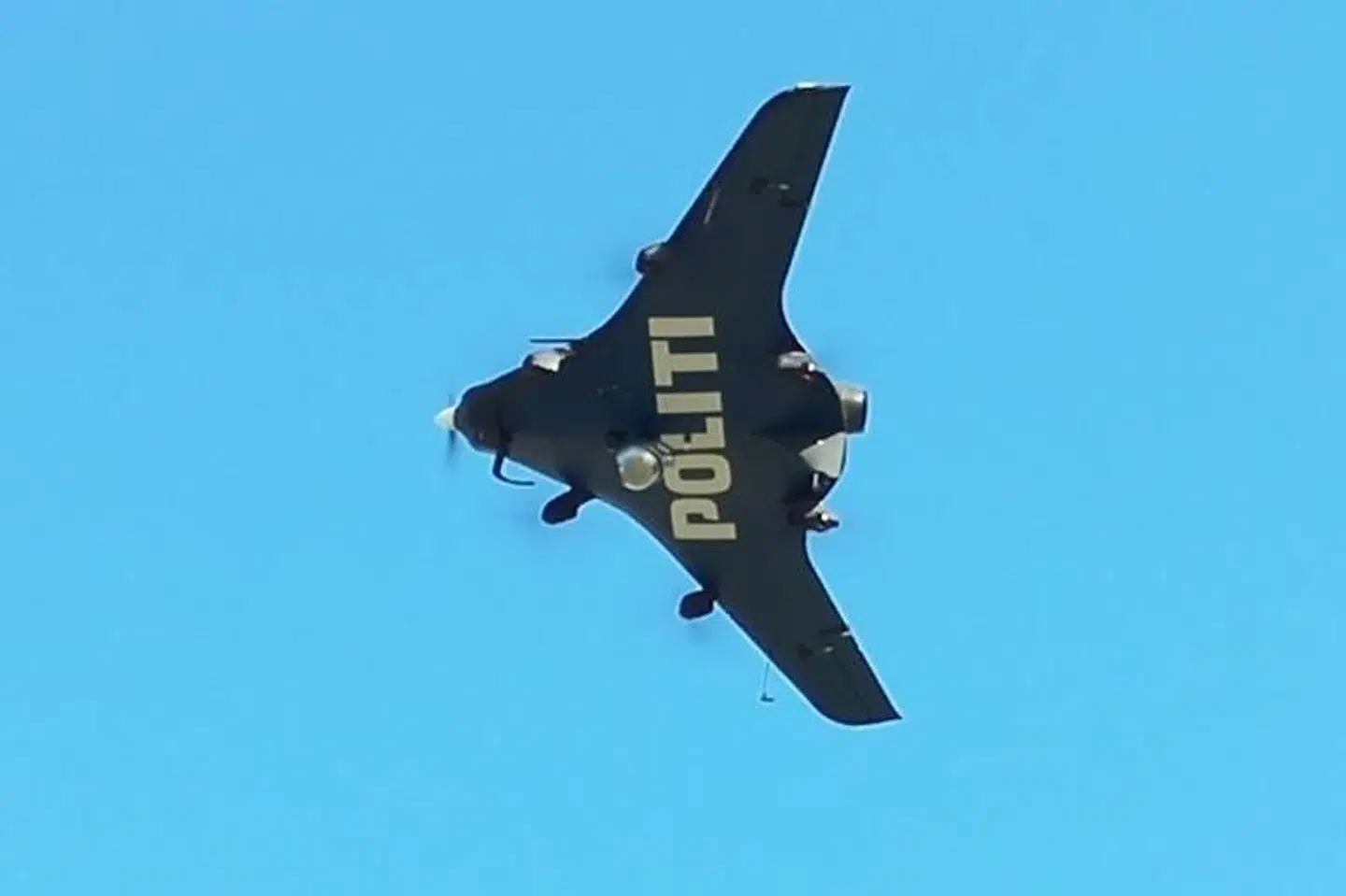 Syd- og Sønderjyllands Politi har delt et billede af en fastvinget drone, hvor der tydeligt står "politi" under, så man kan se det, når den flyver i luften.