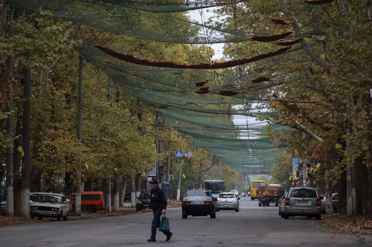 En indbygger krydser i begyndelsen af oktober en gade i byen Kherson, der ligger i det sydlige Ukraine. Et dronenet er spændt ud over vejen. (Arkivfoto).