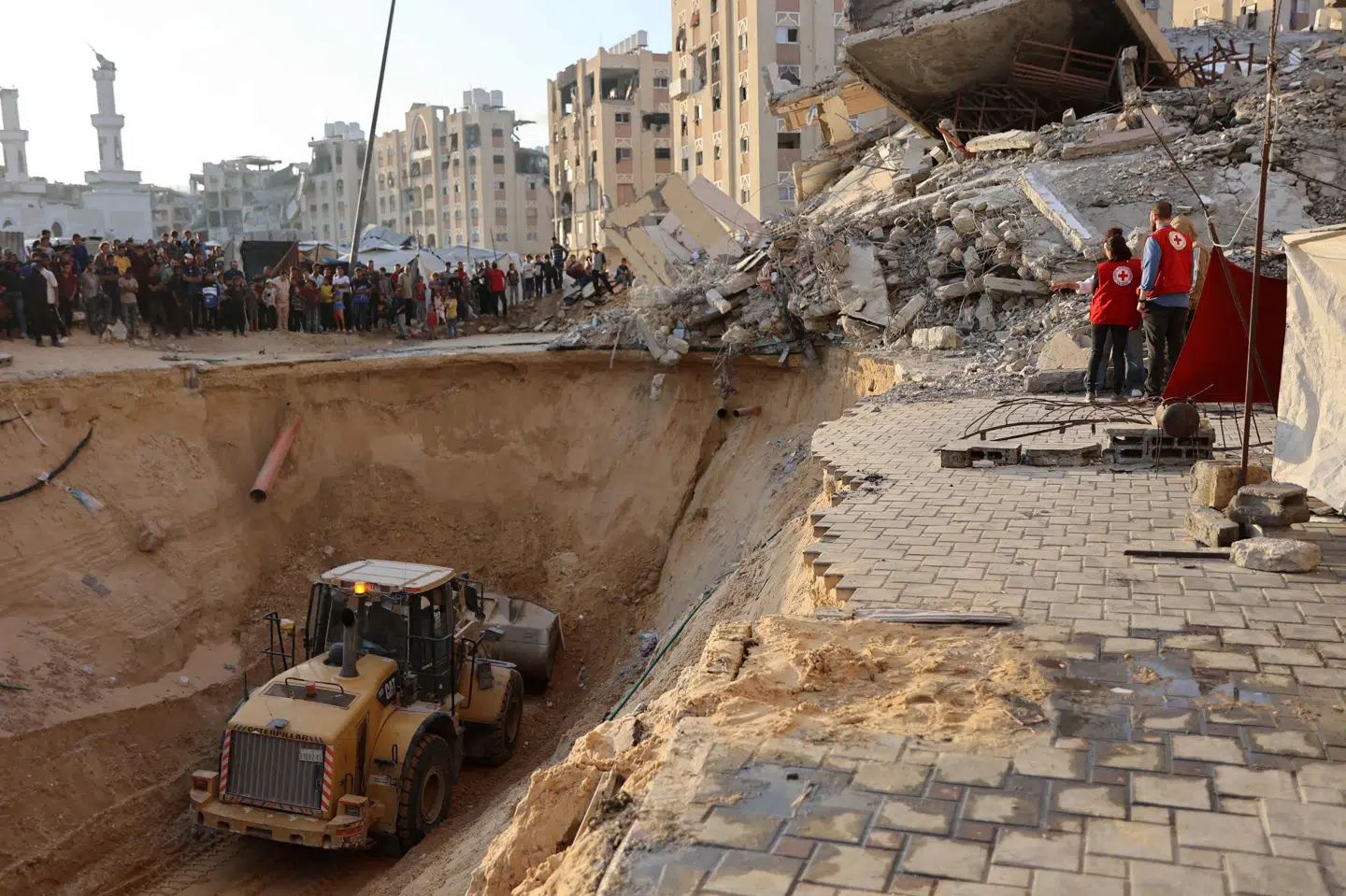Indbyggere i Gazastriben samt nogle medarbejdere fra Røde Kors ser på, mens en bulldozer arbejder i byen Khan Younis i den sydlige del af Gazastriben fredag - angiveligt i et forsøg på at finde de jordiske rester af dræbte israelske gidsler. (Arkivfoto).