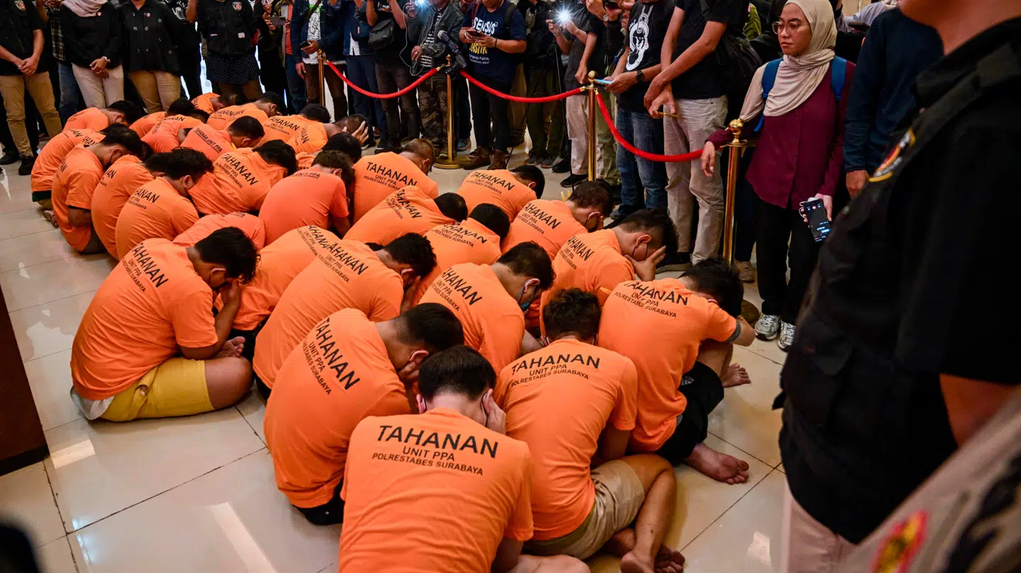 På et billede sidder mændene – klædt i matchende orange skjorter – med benene over kors på gulvet og forsøger at skjule deres ansigter.