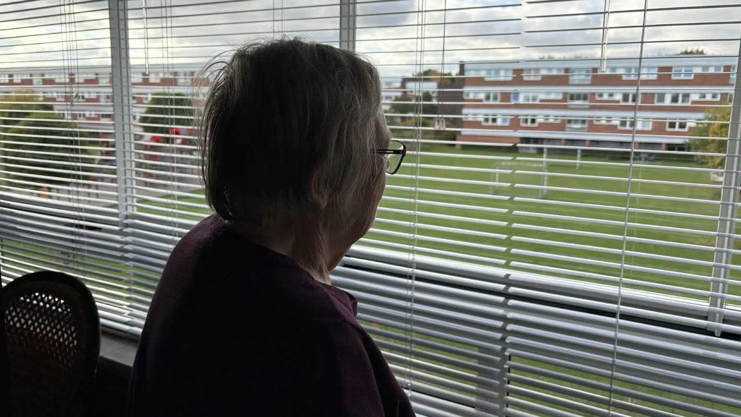 81-årige Inge, der kigger ud af sit vindue fra lejligheden i Glostrup.