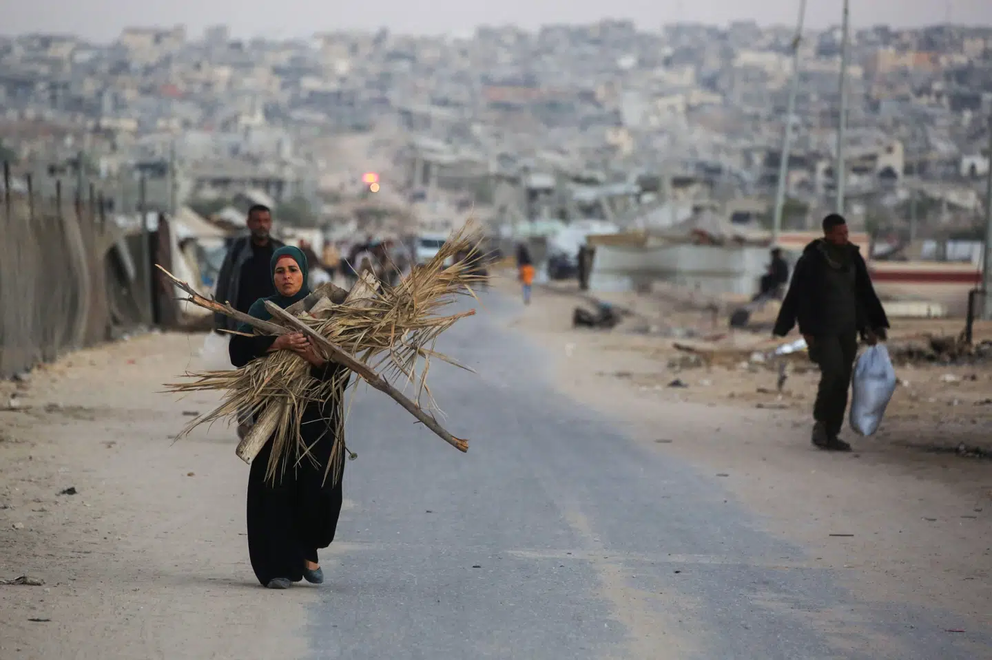 En palæstinensisk kvinde bærer brænde til et bål i byen Khan Younis i den sydlige del af Gazastriben, hvor mange fordrevne palæstinensere har søgt tilflugt. To års krig mellem Israel og Hamas har forvandlet det meste af Gazastriben til ruiner og sendt langt størstedelen af befolkningen på flugt fra deres hjem.