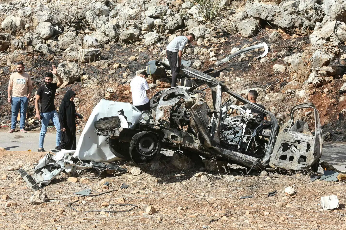 Folk undersøger vraget fra et køretøj, som angiveligt er blevet angrebet af Israels militær i Libanon.