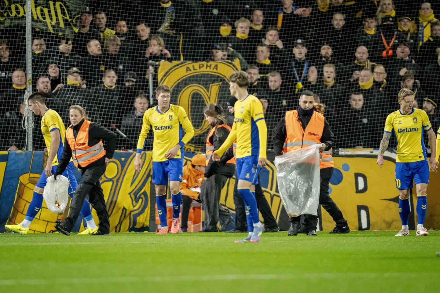 Brøndbyspillere hjalp kontrollørerne med at samle genstande op fra banen, mens mandagens kamp mod OB var afbrudt.
