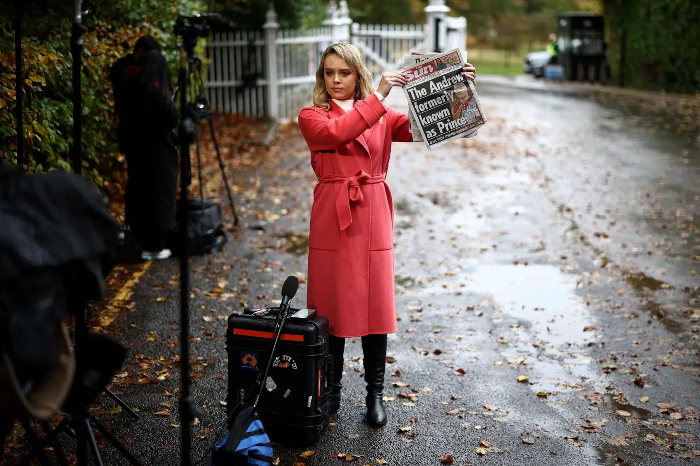En journalist viser mediet The Suns forside fredag morgen foran den tidligere prins Andrews residens, Royal Lodge. Her venter flere medier på, at Andrew Mountbatten Windsor forlader residensen.
