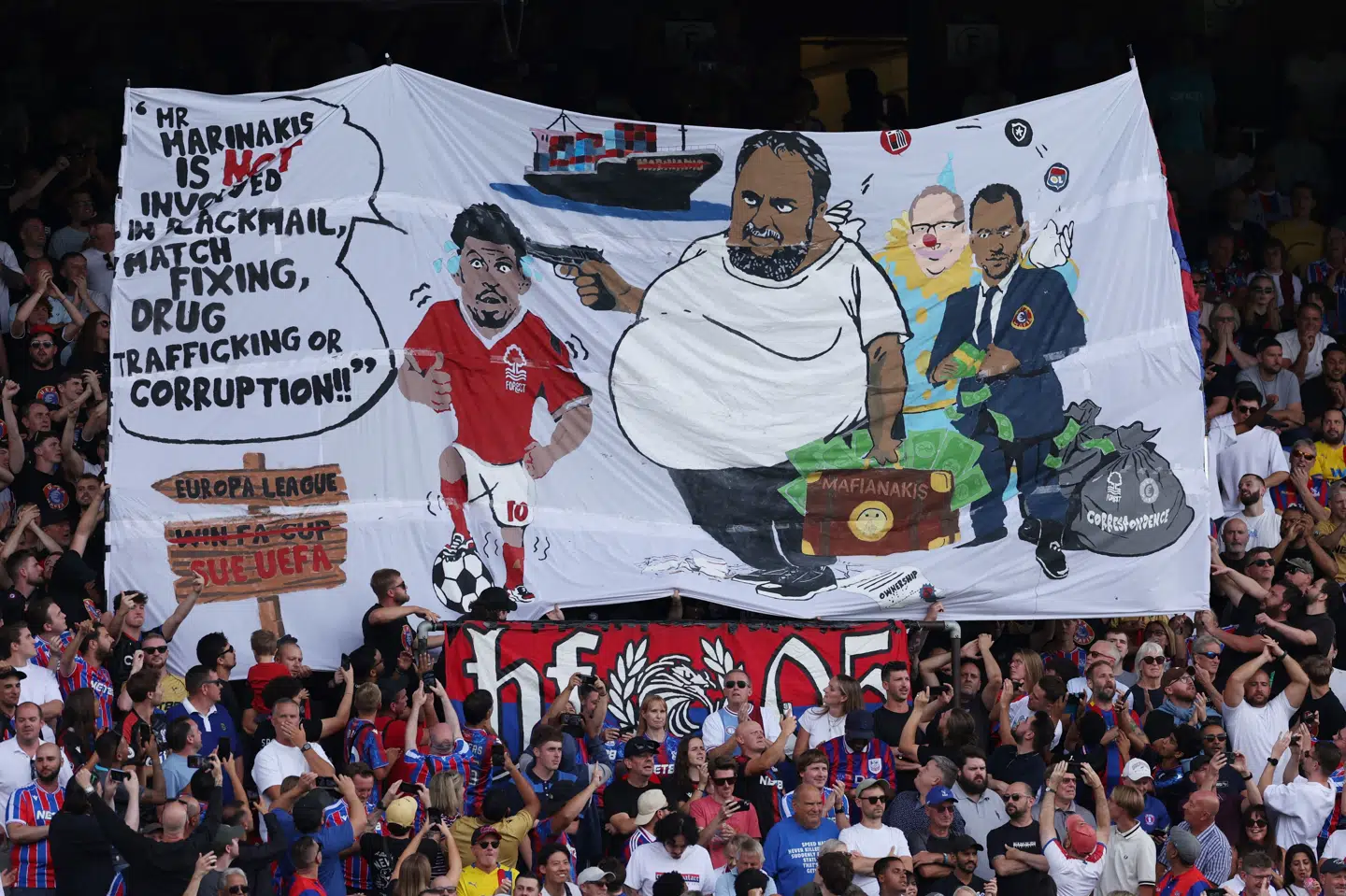 Hr. Marinakis er ikke involveret i afpresning, matchfixing, narkosmugling eller korruption, lyder sætningen på banneret, mens Morgan Gibbs-White har en pistol rettet mod ansigtet. (Arkivfoto).