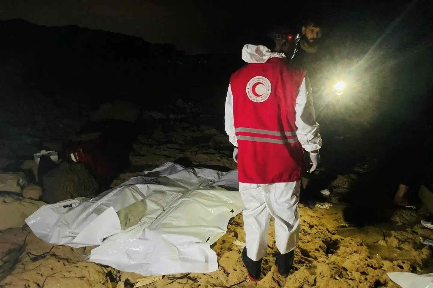 Libyen er blevet et transitland for mennesker, der flygter fra krig og fattigdom. Rejsen over Middelhavet er farlig, og tusindvis af mennesker har mistet livet i forsøget på at nå til Europa. Her står en frivillig fra Røde Halvmåne ved siden af liget af to migranter, efter at en båd kæntrede nær Libyens hovedstad tidligere på året. (Arkivfoto).