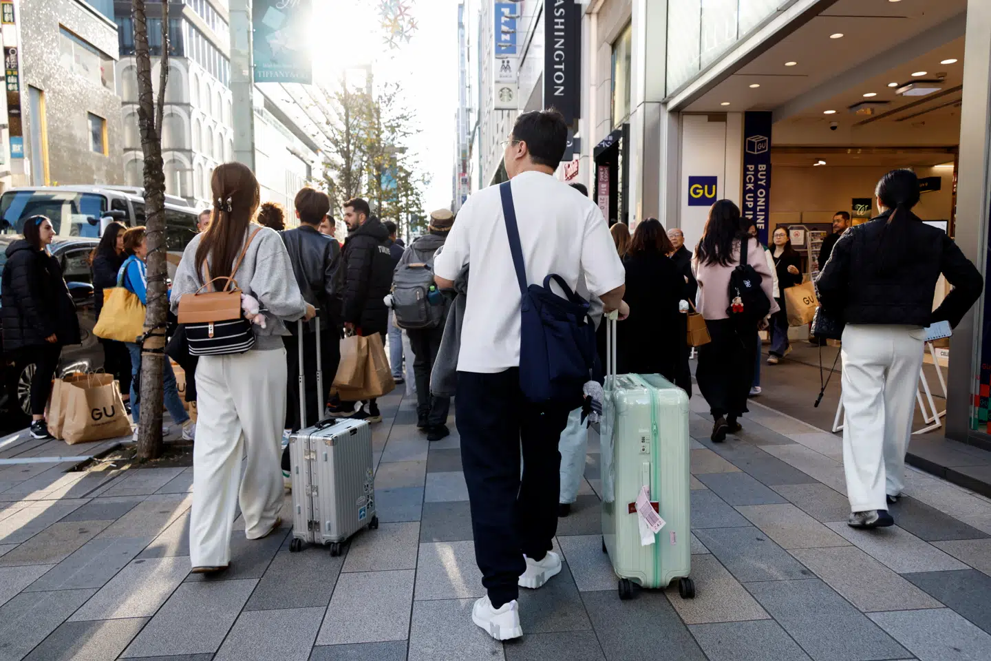 Kinesiske turister ruller kufferterne gennem indkøbsområdet Ginza i Tokyo i Japan. Nu har Kina opfordret kineserne til at blive hjemme.