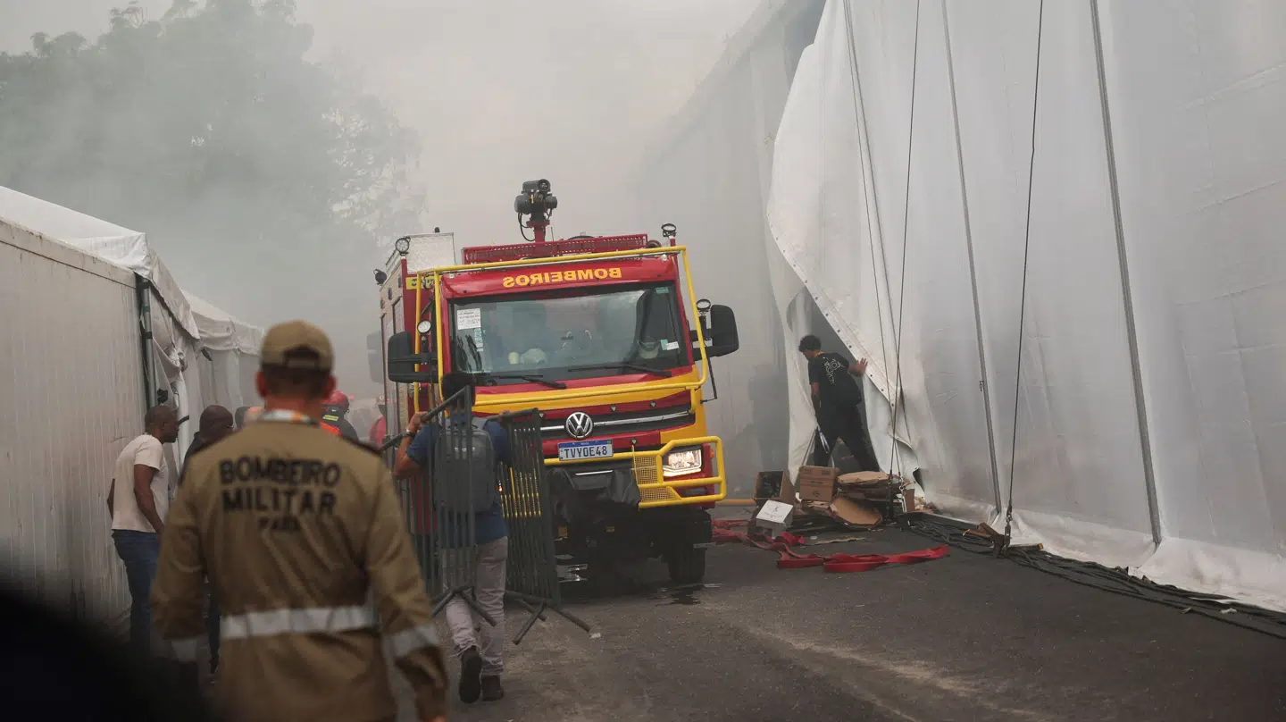 En brandbil holder parkeret ved siden af telte på klimatopmødet COP30 i Belém i Brasilien torsdag, hvor en brand er brudt ud i et telt. Røg kan ses stige op i baggrunden. Brandvæsenet er til stede, og mange deltagere er blevet evakueret.