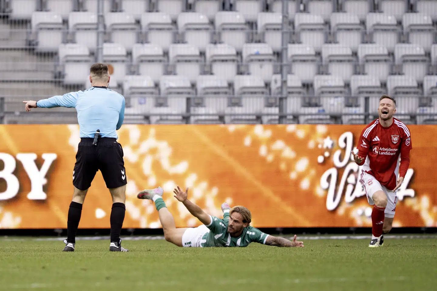 Dommer Svend Funder peger på pletten, efter at Tim Freriks er blevet nedlagt i feltet af Lasse Nielsen, som ærgrer sig.