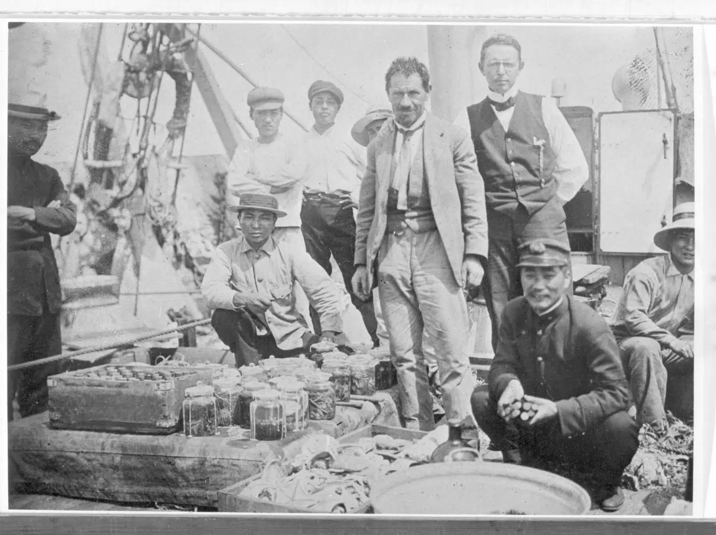 Mortensen og Bock samt mandskab ombord på Hayatori Maru. Forrest ses nogle laboratorieglas fyldt med indsamlede dyr samt en af trækasserne, som glassene kunne pakkes i, når de skulle sendes hjem.