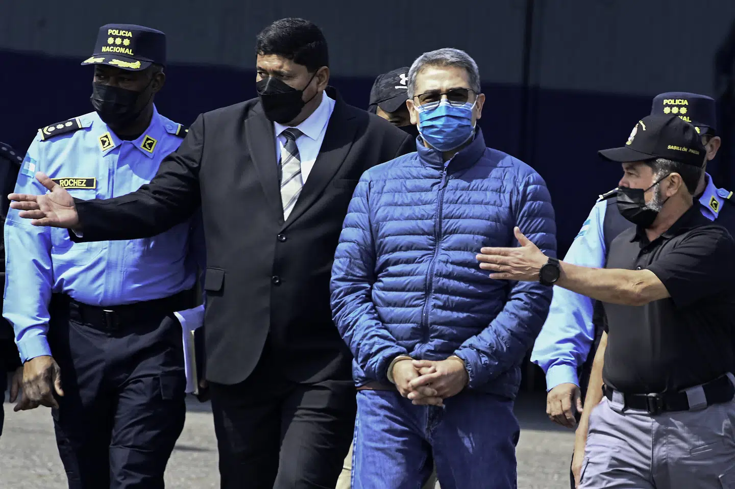 Honduras ekspræsident Juan Orlando Hernandez med det blå mundbind blev i 2022 udleveret fra Honduras til USA, hvor han sidste år blev idømt en dom på 45 års fængsel. Honduras vil have ekspræsidenten anholdt, efter at Donald Trump i november valgte at benåde ham. (Arkivfoto).