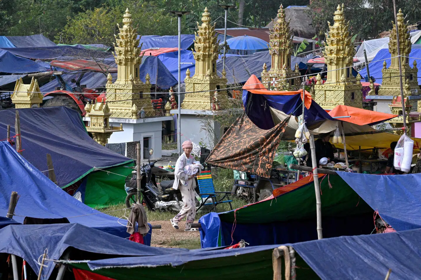 En kvinde bærer torsdag sit barn gennem en lejr, der er sat op for at huse de titusindvis af mennesker, der er blevet evakueret som følge af kampene mellem Thailand og Cambodja ved de to landes fælles grænse.
