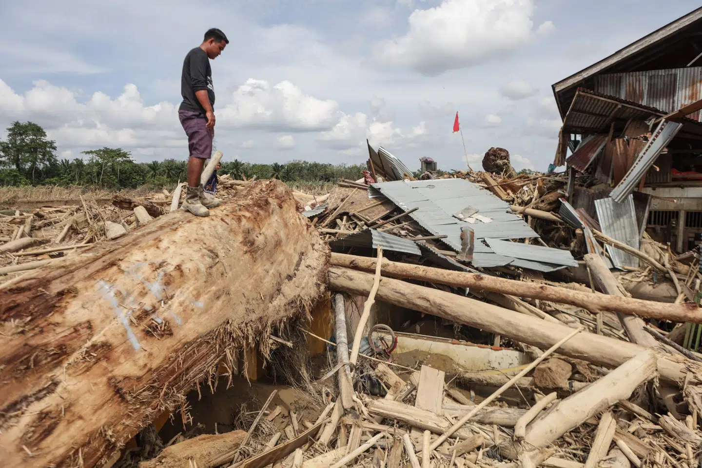 En mand står oven på ruinerne af sit hus i en landsby i Aceh Tamiang i det nordlige Sumatra den 11. december.