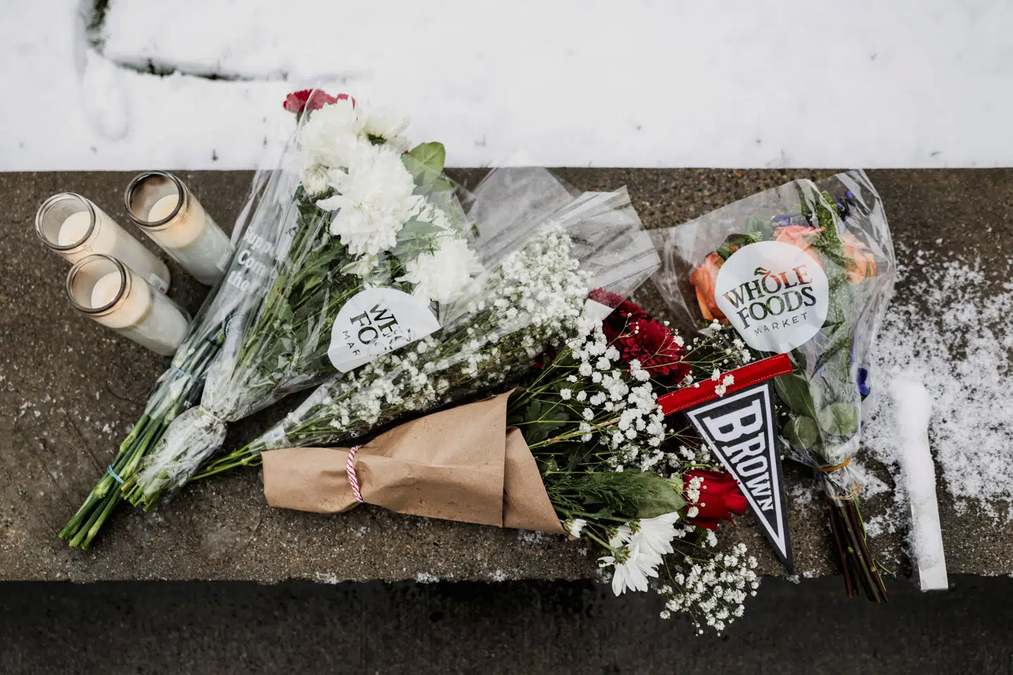Blomster og lys er blevet lagt uden for Brown University, hvor to studerende lørdag blev dræbt af en bevæbnet gerningsmand, som fortsat er på fri fod.