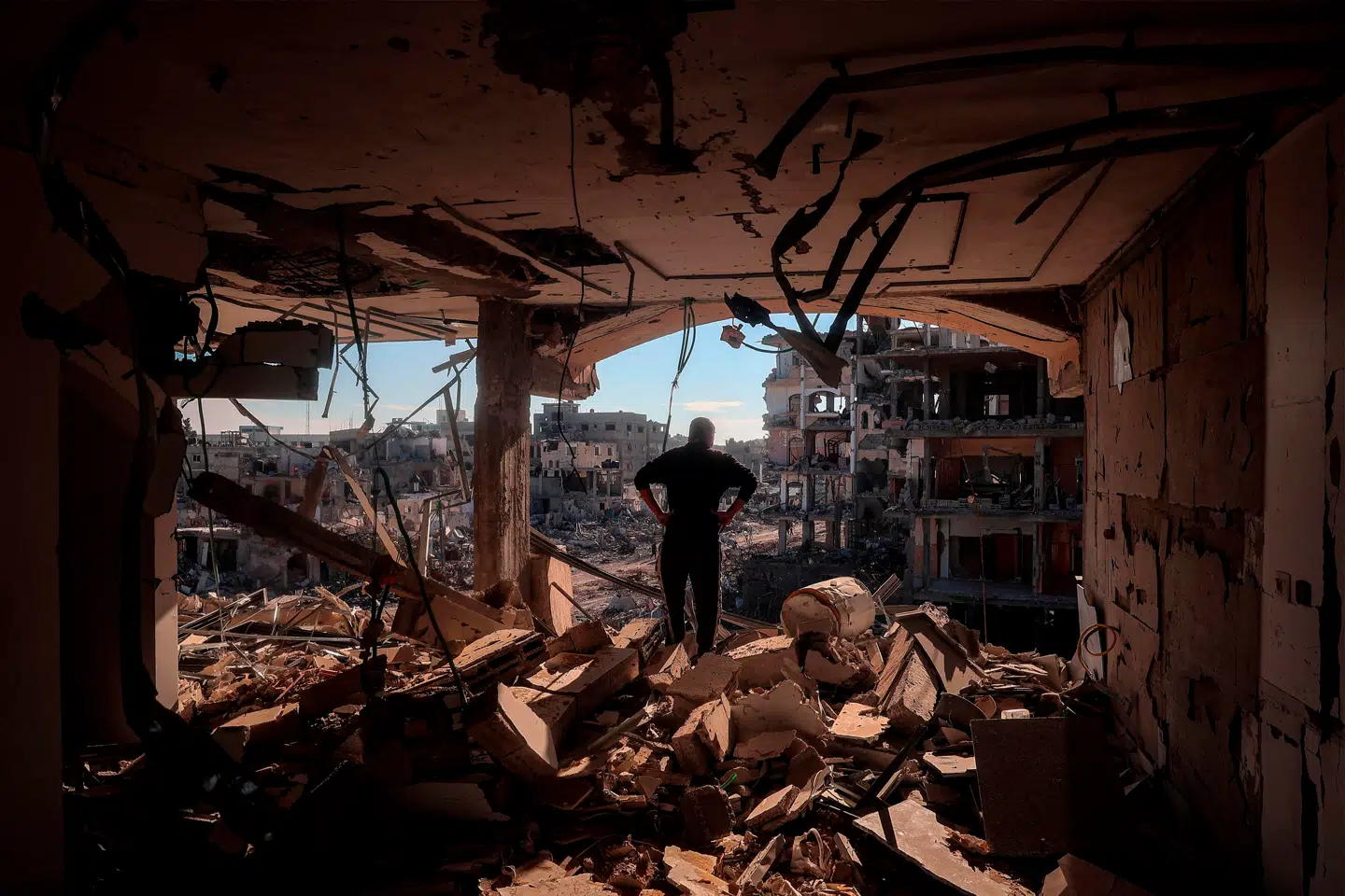 En mand står i en sønderbombet bygning uden vægge i Rafah i den sydlige del af Gazastriben, mens beboere vender tilbage efter våbenhvilen mellem Israel og Hamas.