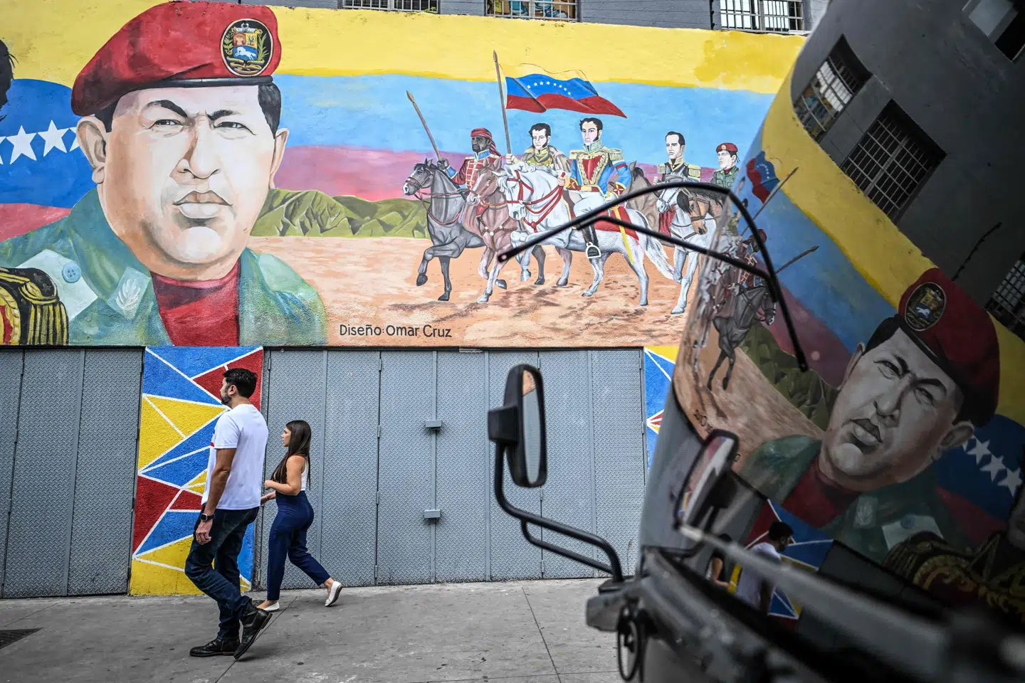 Det statslige olieselskab Petroleos de Venezuela (PDVSA) har onsdag fastholdt, at landets eksport af råolie er upåvirket af melding fra Trump om blokade af sanktionerede olietankere. Billedet er fra Venezuelas hovedstad, Caracas, onsdag, hvor indbyggere kan ses passere vægmaleri af den tidligere præsident Hugo Chavez.