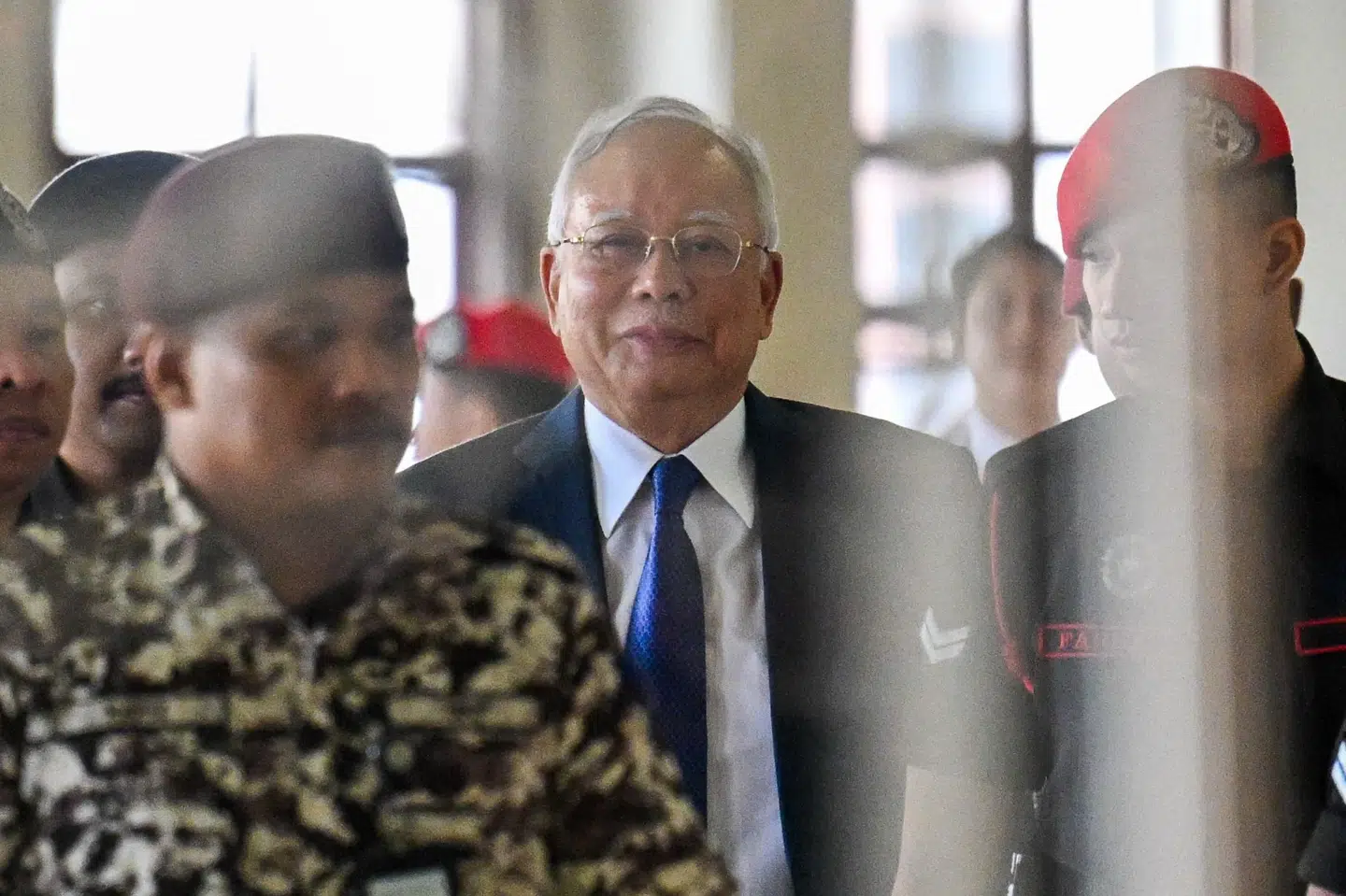 Najib Razak, der her går sammen med fængselsbetjente under et retsmøde i 2024, har løbende erklæret sig uskyldig i en sag om underslæb i den statslige fond 1MDB i Malaysia. (Arkivfoto).