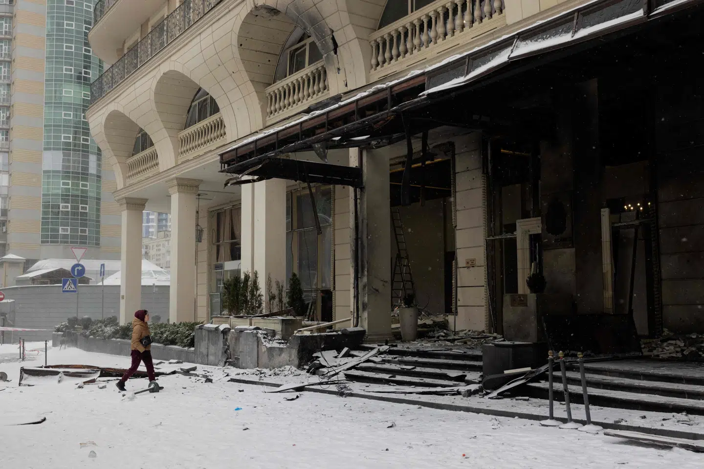 En kvinde går i januarkolde Kyiv ind i en beskadiget boligbygning efter omfattende russiske angreb fredag.