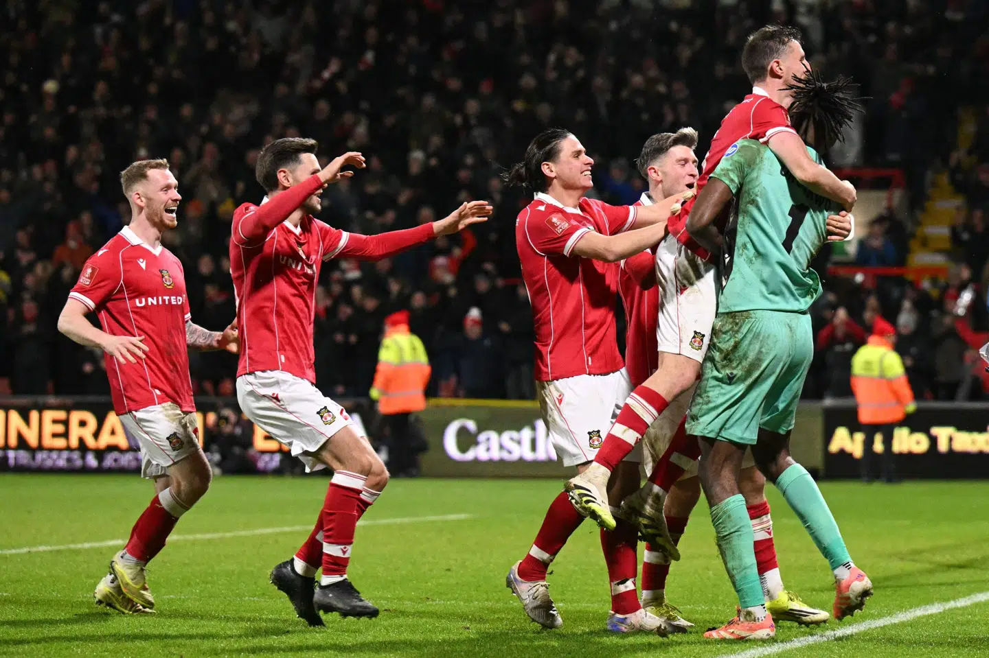 Wrexhams spillere omfavner holdets målmand, som netop har snuppet det afgørende straffespark i FA Cup-opgøret mod Premier League-klubben Nottingham Forest.
