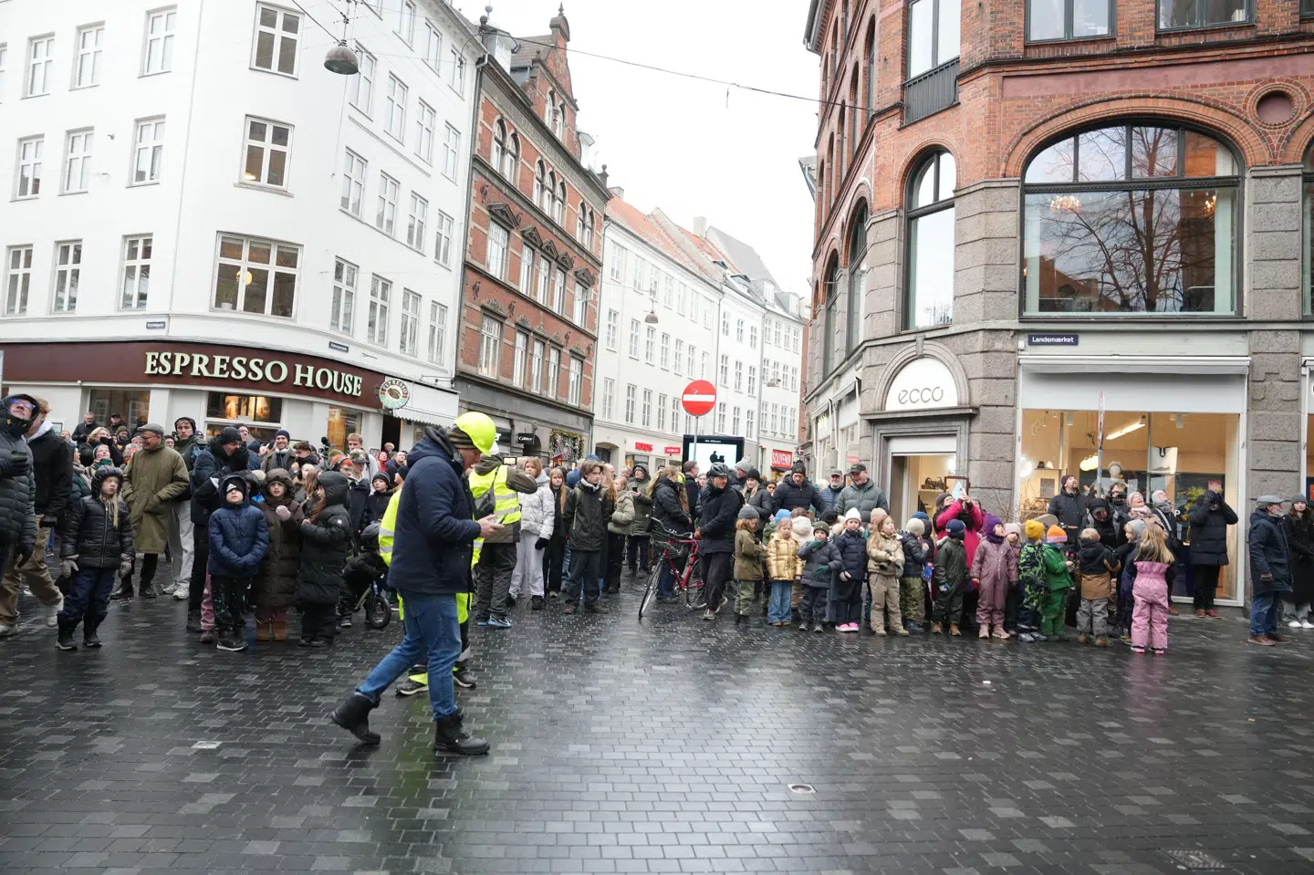 På gaden foran Rundetårn i København står mennesker og kigger op på kranen, der hejser den tre ton tunge kobberkuppel ned mandag.