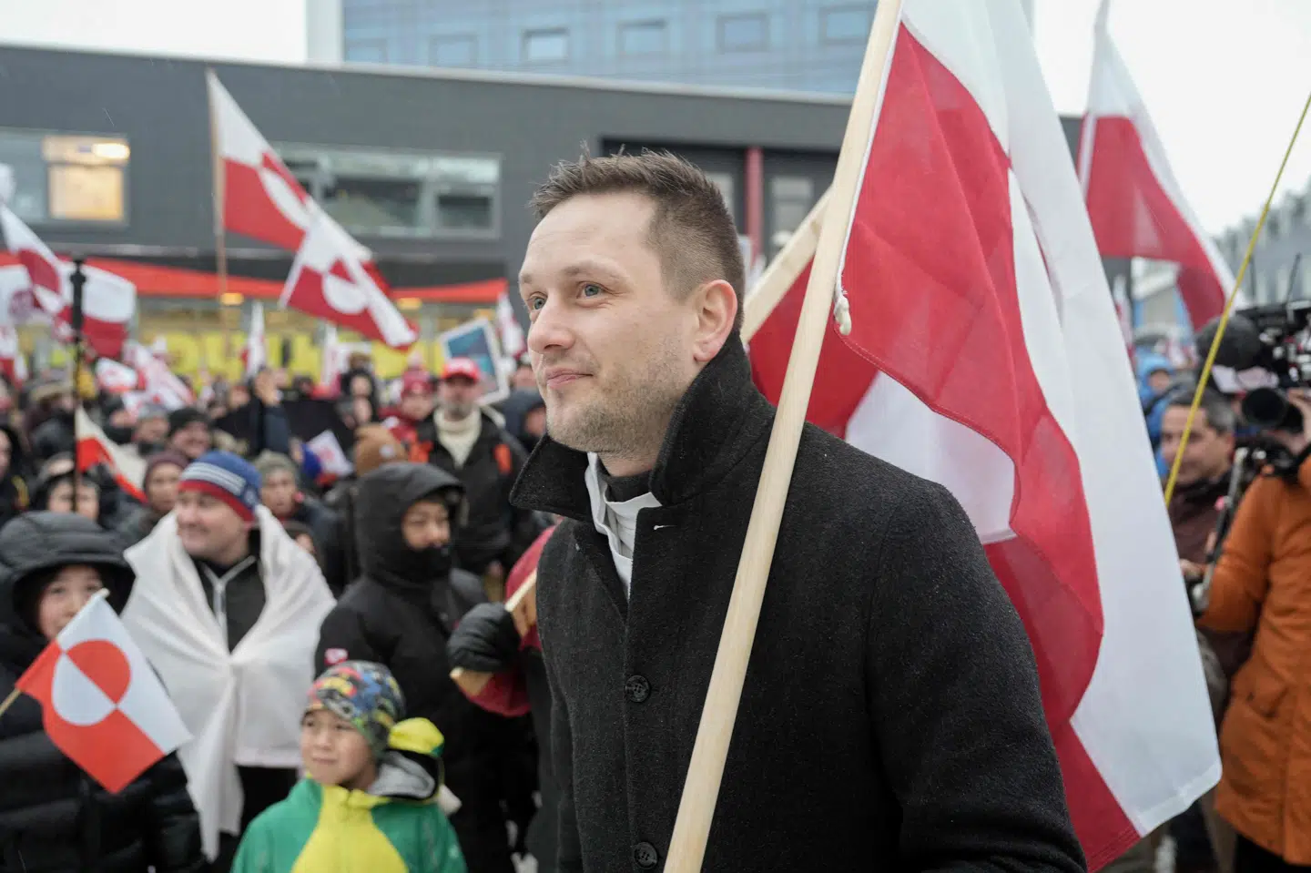 Formand for Naalakkersuisut, Grønlands regering, Jens-Frederik Nielsen, bærer et grønlandsk flag over skulderen til demonstrationen i Nuuk.
