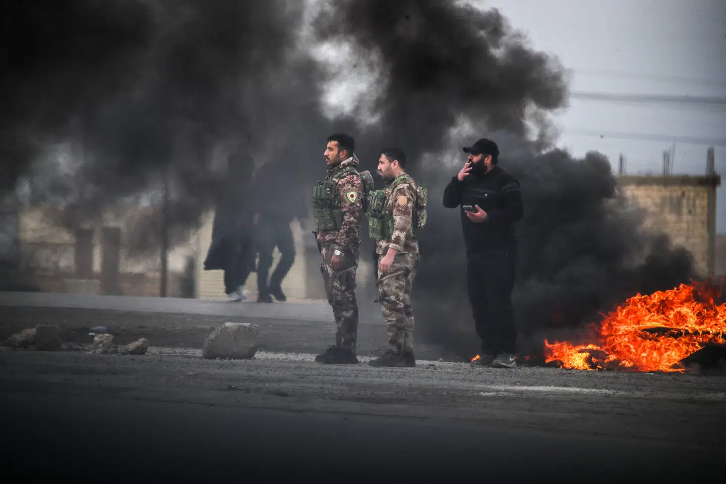 Kurdiske soldater står ved indgangen til byen Tabqa i det nordlige Syrien lørdag, efter at de har trukket sig tilbage fra territorier, som de har haft kontrol med i over et årti. Den syriske hær har erobret dele af det nordlige Syrien for at lægge pres på kurderne for en løsning med en regering, der både er kurdisk og syrisk.