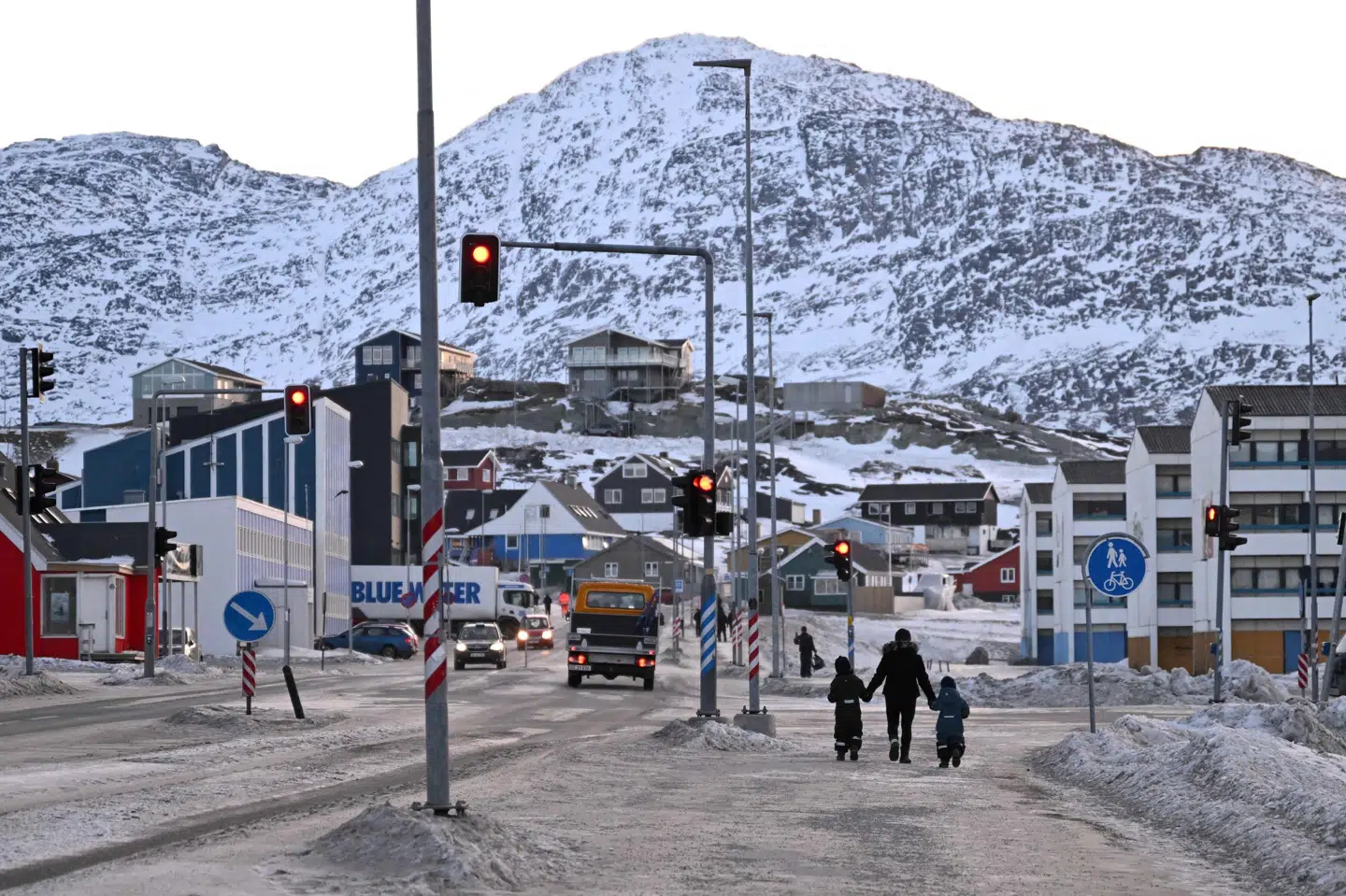 En kvinde går mandag på fortorvet med sine to børn i den grønlandske hovedstad, Nuuk. Ministre fra den grønlandske regering fortalte mandag, at forældre kan finde hjælp i to brochurer til, hvordan de kan fortælle deres børn om verdenssituationen.