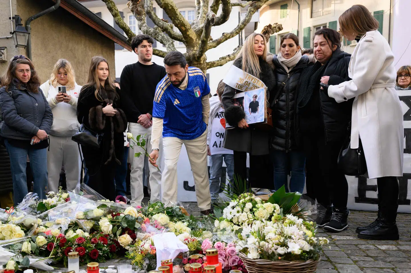 En far til et af ofrene i dødsbranden i Crans-Montana lægger en blomst under lørdagens march i Lutry.