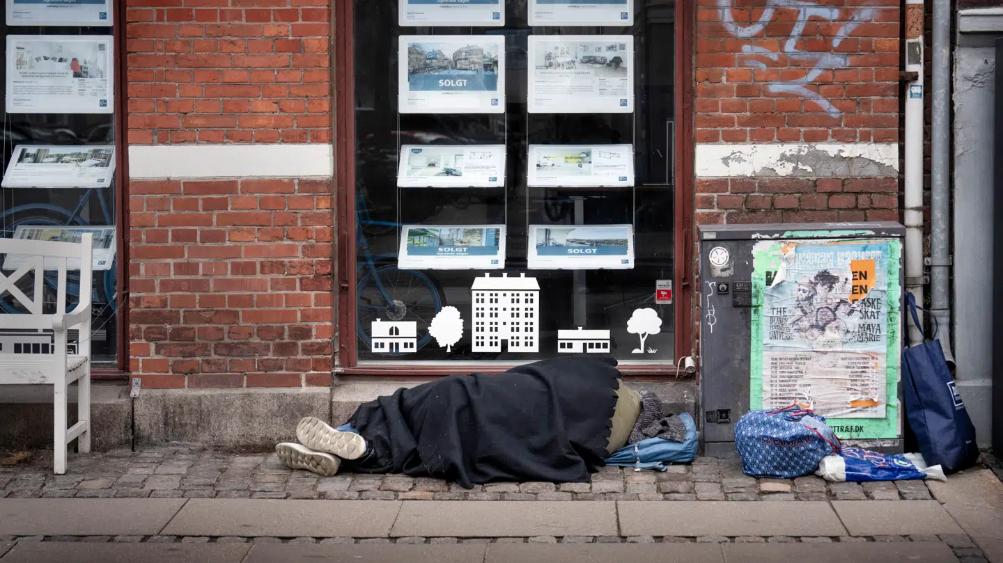 Hjemløs sover foran en ejendomsmægler i København.