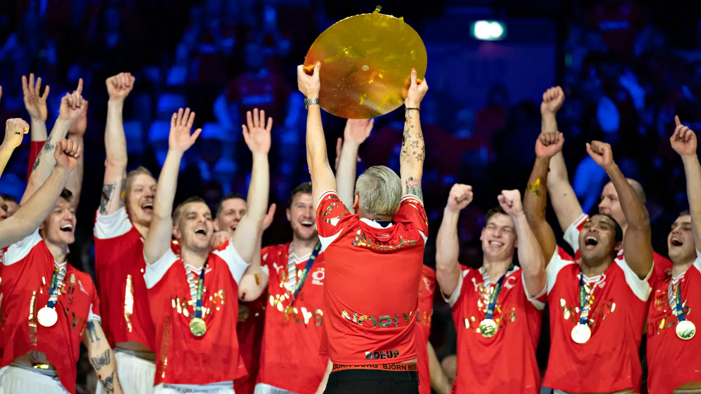 Danmarks cheftræner Nikolaj Jacobsen løfter trofæet foran de danske spillere søndag aften.
