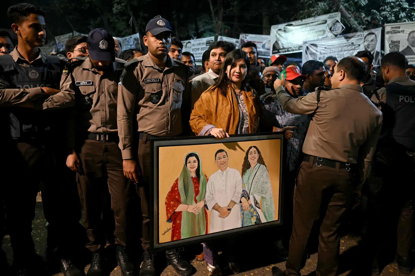 En tilhænger af BNP ses fredag med et billede af partiets formand, Tarique Rahman, der ventes at blive landets nye premierminister. På billedet ses også hans hustru, Zubaida Rahman, til venstre og datteren Zaima Rahman.