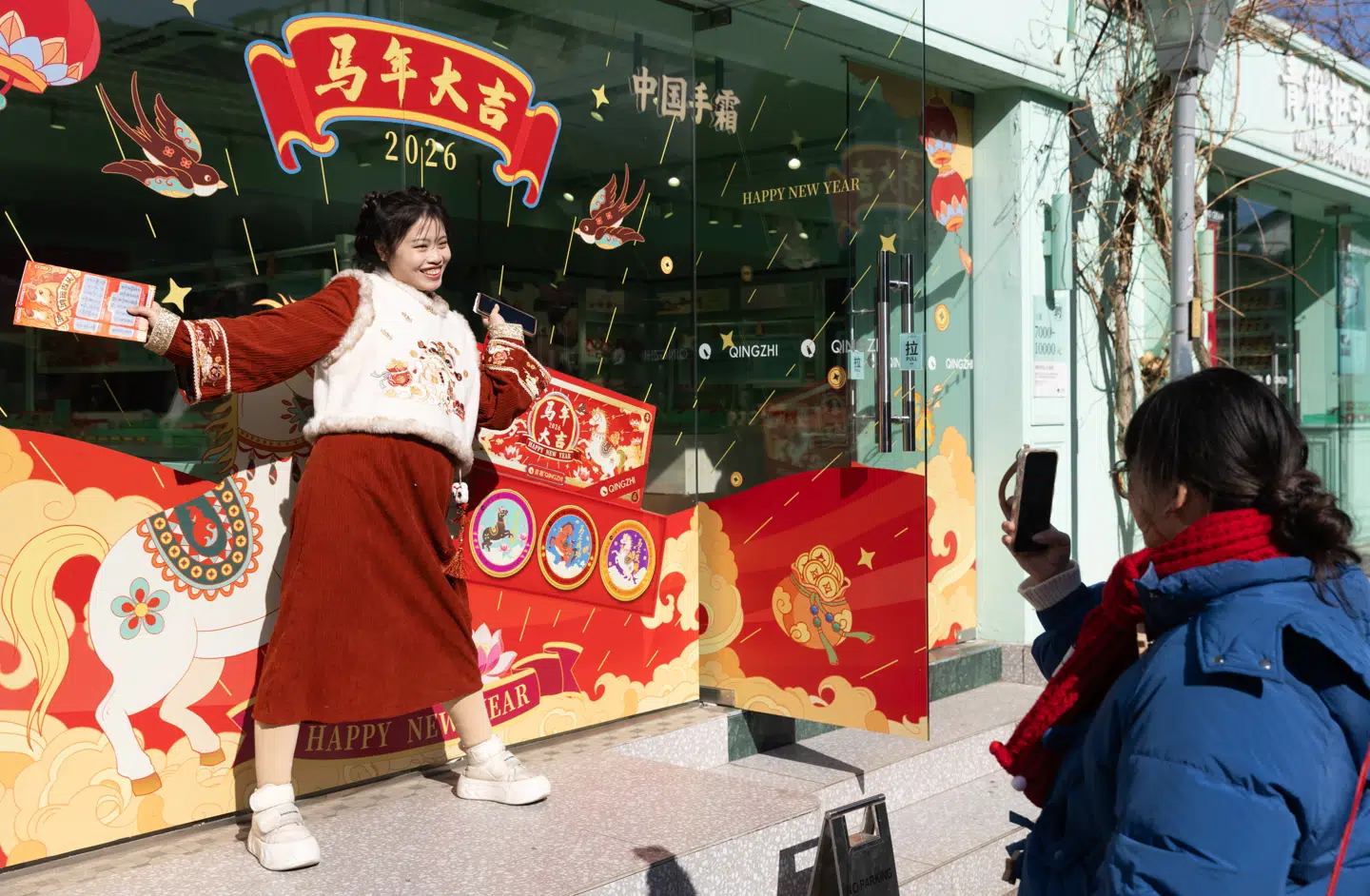 Kineserne fejrer nu nytåret, som er årets store fest. Her poseres der foran en nytårsudsmykket butik i Beijing.