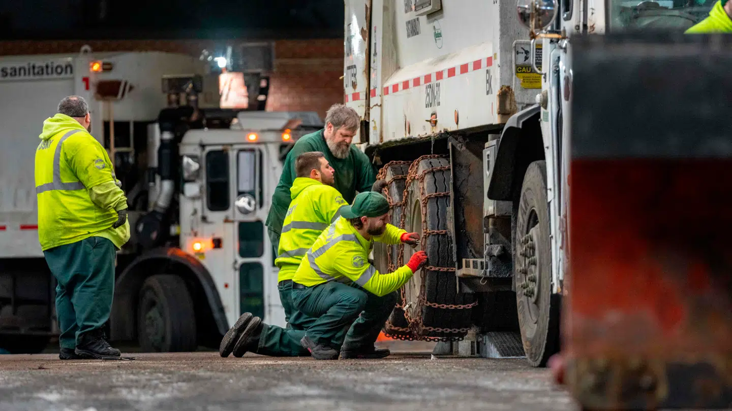 I New York City er man i fuld gang med at forberede sig på den kommende vinterstorm. Her ses renovationsarbejdere sætte kæder rundt om dækkene, så man fortsat vil kunne køre ud.